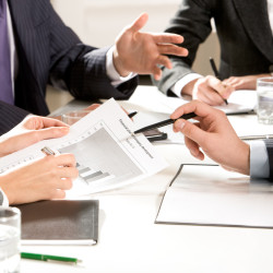 Close-up of business people hands with pens during explanation at meeting